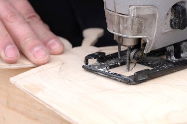 Elektrik jig gördüm ahşap iş için iş parçası, aracı ve gri ahşap arka plan efendinin elini tutar