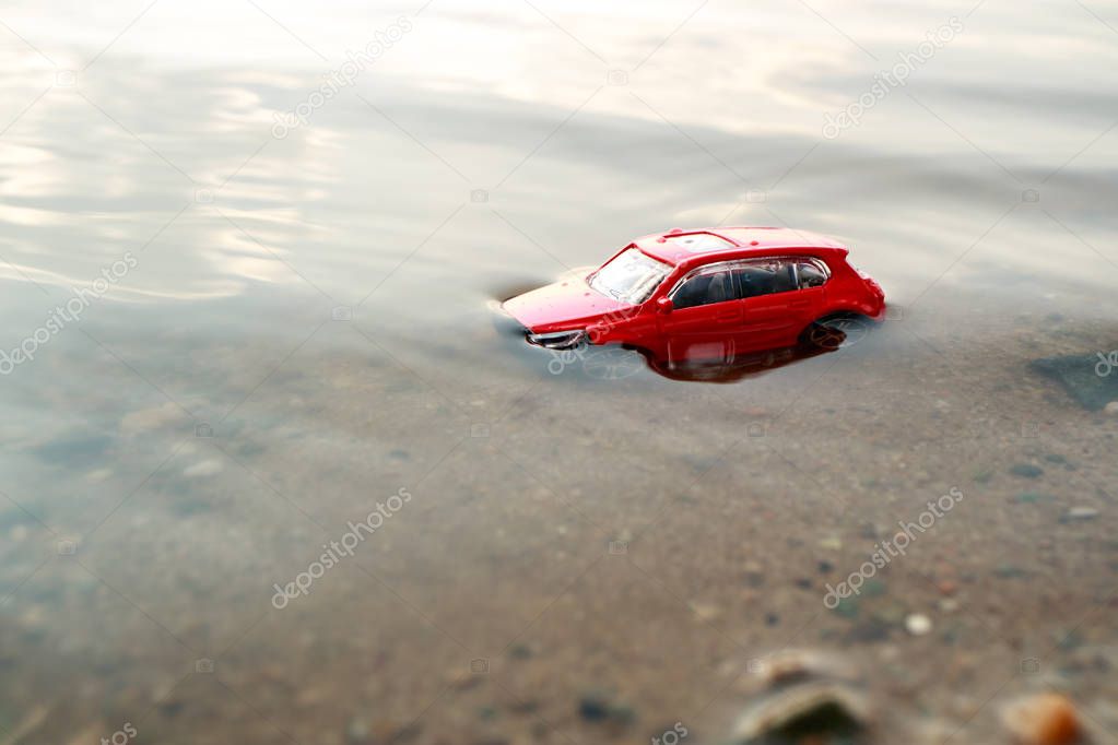 toy car almost drowned in the water on the shore of the pond on a summer day, sticking out of the water only the roof, the accident on the pond