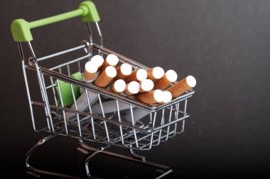 lots of cigarettes stacked in shopping basket filters to us, buying cigarettes wholesale, dark background clipart