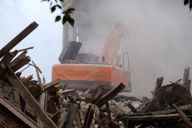 binanın yıkılması teknoloji, toz ve traktörün tekerlekleri altında bina enkazı etrafındaki ağaçlarla yardımıyla