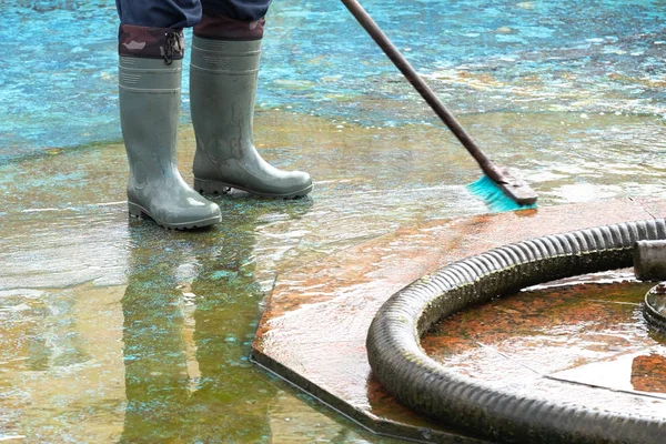 fountain cleaner on the street, washes the surface of the fountain inside where water flows, hose and brush for cleaning dirt