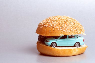 bir hamburger üzerinden bir topuz yarısı arasında araba oyuncak, arabadaki kahvaltı vardır