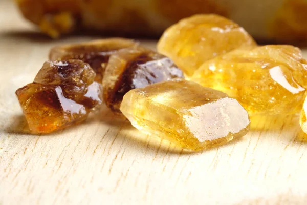 shiny pieces of brown cane sugar on light wood