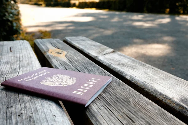 夏天的一天 俄罗斯护照在木长凳上 背景是公园里铺就的小路 — 图库照片