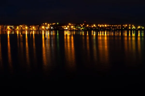 城市的灯光反映在水面上 黑暗中地平线上的一条狭窄的光线 — 图库照片
