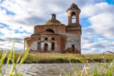 eski kilise ve gökyüzünde bulutlar ve ön plan gölet ve çim ile harap