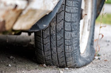 kirli asfalt üzerinde düz tekerlekler ile eski terk edilmiş araba