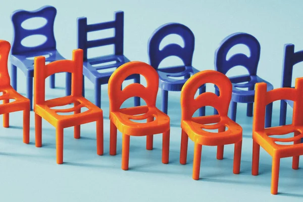 red and blue chairs standing in two rows on a blue background, first row red second row blue, toy chairs