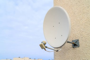 Tv sinyali almak için bir uydu çanağı beyaz duvara cıvatalı