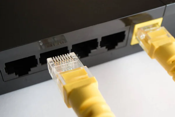 En korskopplingskabel är isatt i den gula kontakten av routern — Stockfoto