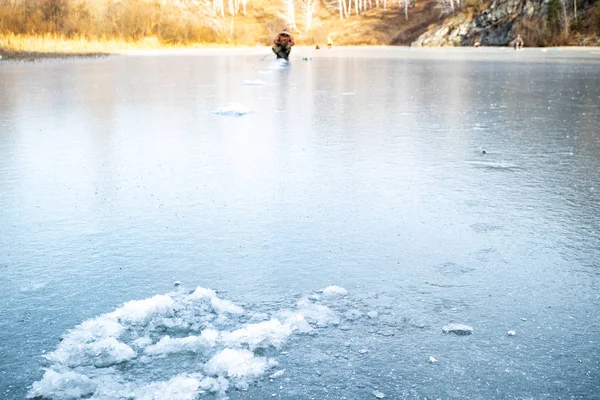 Transparentes Eis auf dem Teich, in der Ferne sitzt ein Fischer — Stockfoto