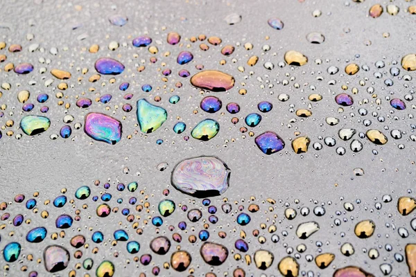 Goccioline d'acqua mescolate con prodotti petroliferi, a causa di questo sull'acqua diversi modelli di colore diverso — Foto Stock