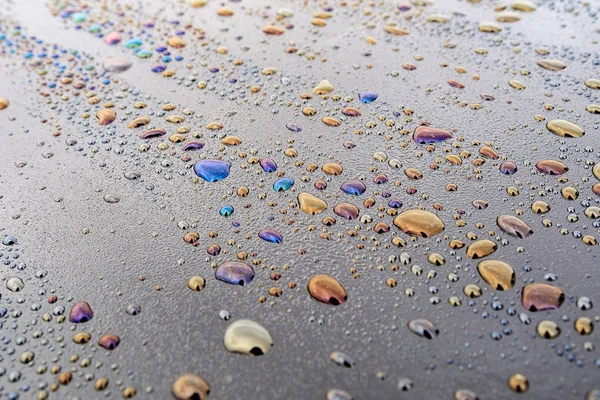 File di gocce d'acqua che si trovano sulla superficie bituminosa, sulle gocce di diversi colori macchie — Foto Stock