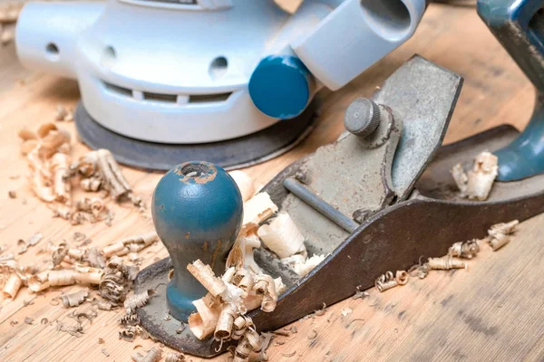 electro sander and manual old plane on a wooden surface