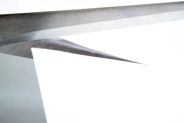 Большие металлические ножницы режут белый лист бумаги, угол формируется между ножницами — стоковое фото