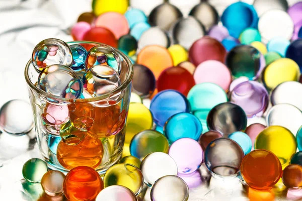 Beaucoup de boules d'hydrogel sur du papier d'aluminium et une pile de vodka remplie de boules d'hydrogel — Photo