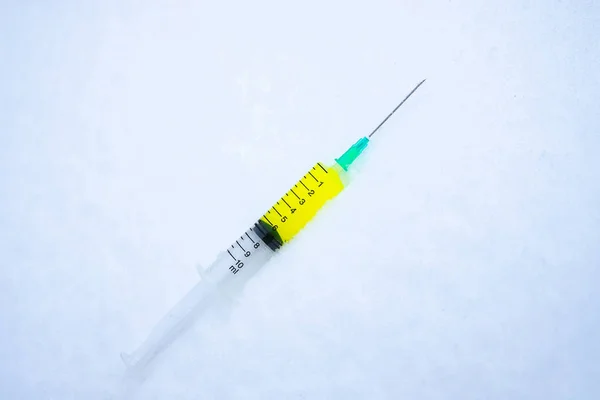 Spritze mit gelber Flüssigkeit liegt auf dem Schnee, ein gefährlicher Impfstoff — Stockfoto