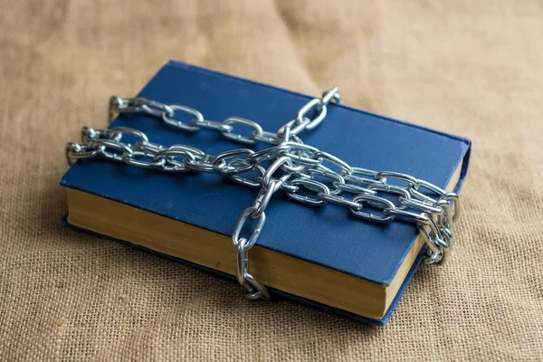 burlap üzerinde yatan mavi kapaklı bir kitabın üst görünümü, kitap bir zincir, yasak bir kitap sarılır