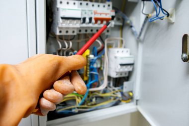 elde kauçuk eldiven, bulanık arka plan üzerinde kırmızı tornavida ile elektrik tesisatlarında güvenli çalışma