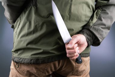 bir adam büyük bir şef bıçağı, yeşil ceket sarı pantolon geri tutar
