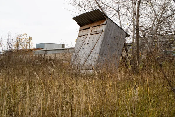 乾いた草の中の白い空に対してほとんど倒れた建物、忘れられた建物 — ストック写真
