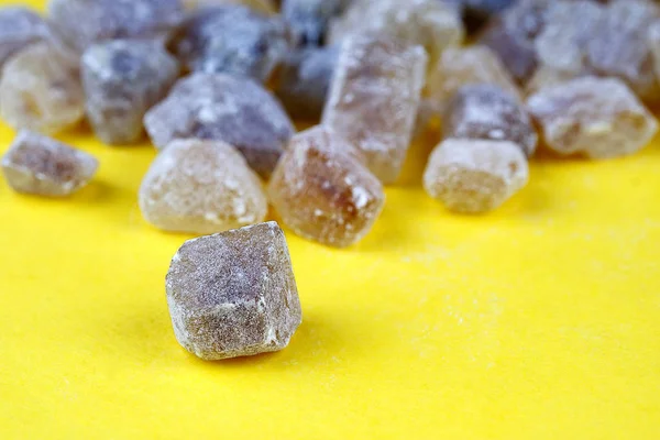 黄色の背景に散乱キャラメル塊サトウキサケ砂糖 — ストック写真