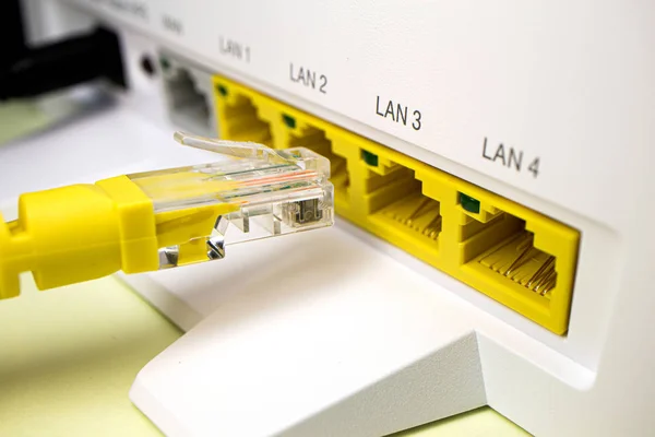 带 rj45 连接器的黄色电缆插入家庭路由器，用于互联网 — 图库照片