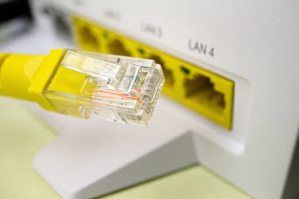 Koneksi ke jaringan lokal melalui router rumah, patch cord kuning closeup di latar belakang — Stok Foto