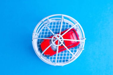 kırmızı oyuncak araba bir kuş kafesi üst görünümünde kapalı, kafes mavi olduğu yüzey