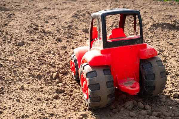 Rear view of a red tractor made of plastic, a tractor on a field of dry brown — Stock Photo, Image
