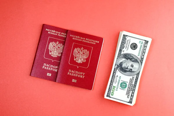 Δύο ρωσικά διεθνή διαβατήρια σε πορτοκαλί φόντο βρίσκονται δίπλα στα δολάρια — Φωτογραφία Αρχείου