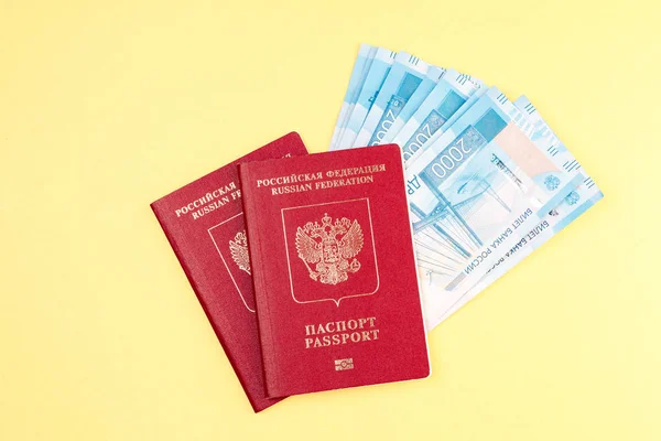 Σε κίτρινο φόντο, δύο διαβατήρια της Ρωσίας για ένα ταξίδι στο εξωτερικό επένδυσαν χρήματα — Φωτογραφία Αρχείου