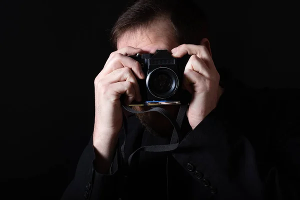 Uomo con una vecchia macchina fotografica su uno sfondo scuro — Foto Stock