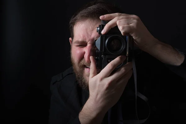 Un uomo barbuto su uno sfondo scuro in un fotografo giacca scura — Foto Stock