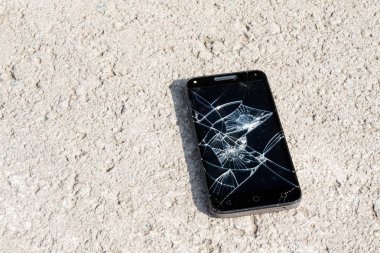 kırık bir ekran ile küçük taşlar akıllı telefon arasında kaldırımda yatan
