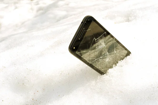 De pie medio en el teléfono inteligente de nieve con una pantalla rota —  Fotos de Stock