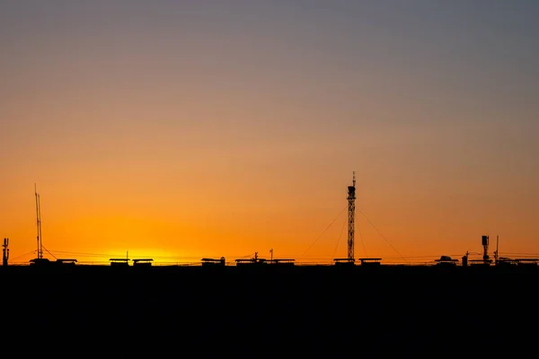 sunset city rooftops with antenna and lots of cables