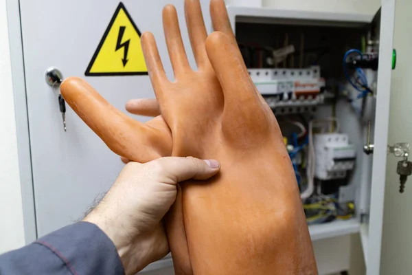 dielectric gloves in hand holds the employee in front of the electrical panel in the room