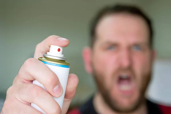 screaming man blurred out of focus in the background hand in the foreground with insect spray