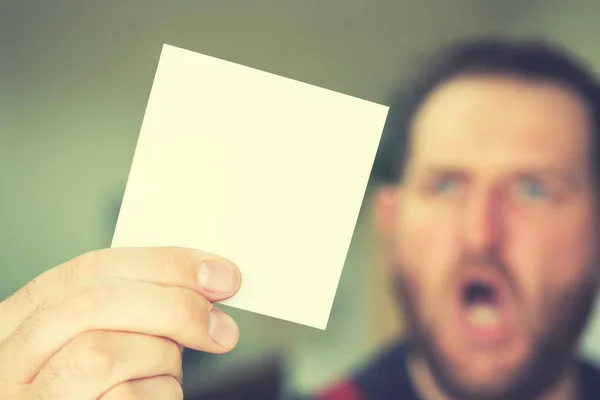 Surprised man holding a blank sheet of square shape — Stock Photo, Image