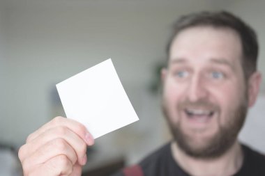 ön planda arka planda mutlu adam elinde boş kare şeklinde bir kağıt parçası