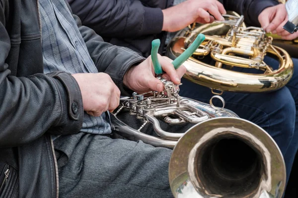 a street musician repairs a broken musical instrument on the spot