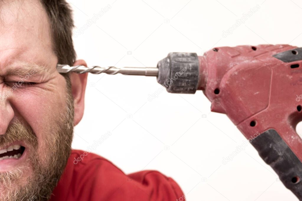 close-up a white man with a beard pointed a power drill at his temple like a gun and closed his eyes