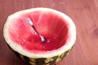a sliced red ripe watermelon with a spoon stuck in it. spoon ate watermelon like a cup clipart
