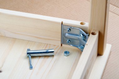 Bir tabloyu ağaçtan monte etme süreci. Tezgahın üstünde vidalanmamış bir somun yatıyor.