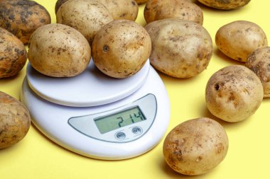 potatoes on small household scales. weighing purchased potatoes for verification clipart