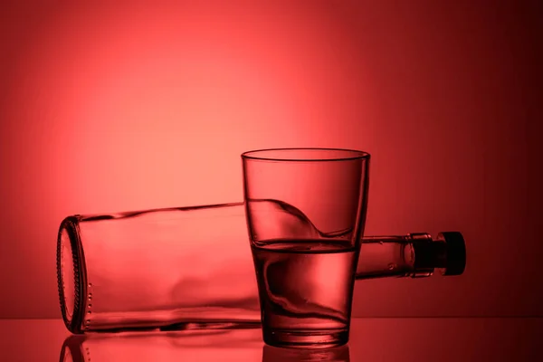 Vetro Con Liquido Una Bottiglia Sdraiata Una Superficie Vetro Rosa — Foto Stock