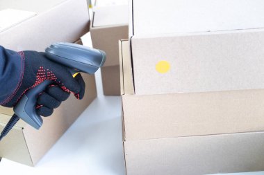 Eldivenli bir el, kutuya nişan almış bir barkod okuyucusunu tutuyor. veri girdisi