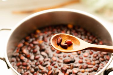 Çam fıstıklı ahşap kaşık, arka planda fındıklı ve suya batırılmış bir tava. Kabuğun yumuşaması için ıslatma ve pişirme işlemi.