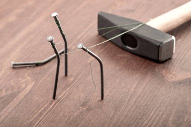 Tahta bir masaya büyük bir çekiçle bağlanmış çiviler. Sosyal adaletsizlik insanları ve hükümet yetkilileri